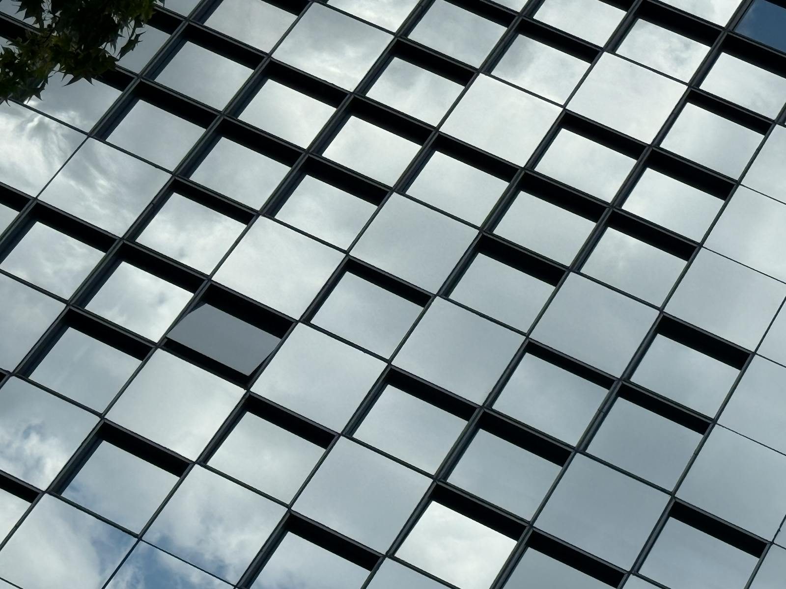 Photo by David Munoz Abstract view of a building facade with mirrored glass squares reflecting the sky.